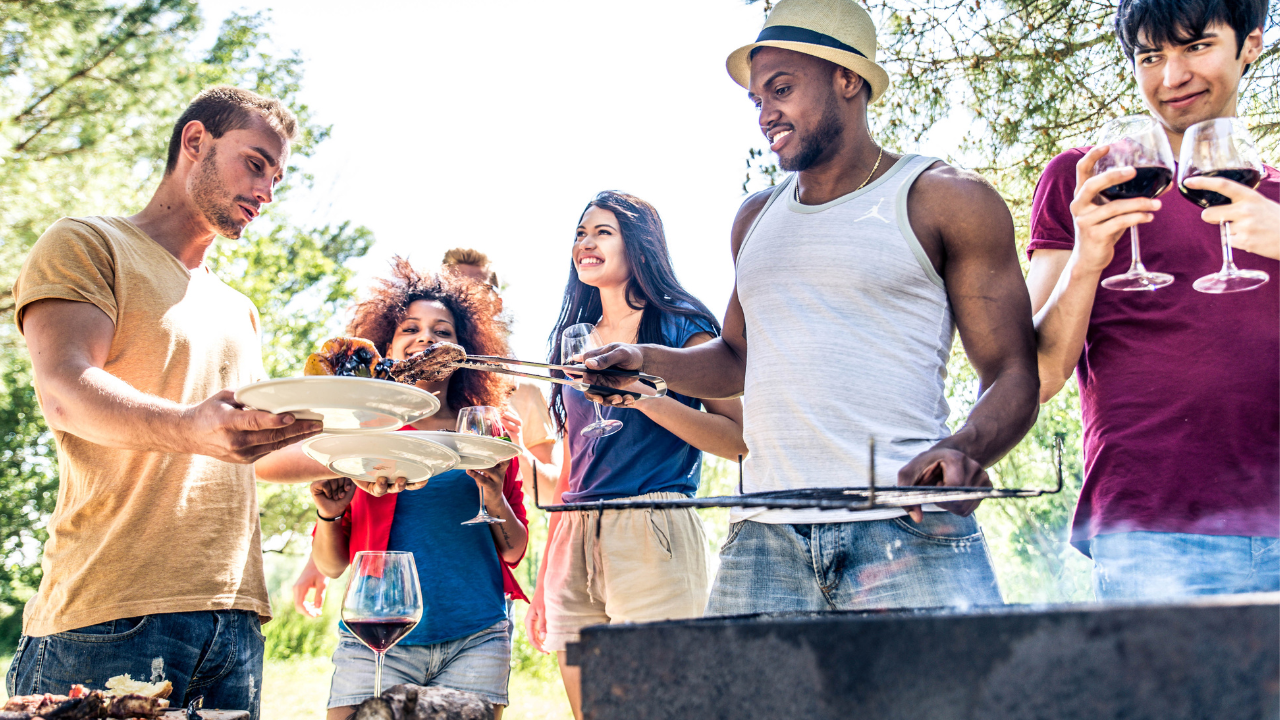 Young people standing around a grill 