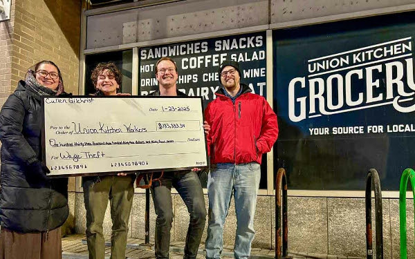 UFCW members pose with a novelty check in front of a Union Kitchen location.