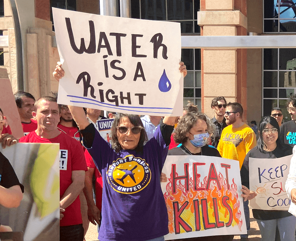 A woman holding a sign that says, "water is a right" at a heat rally in Arizona