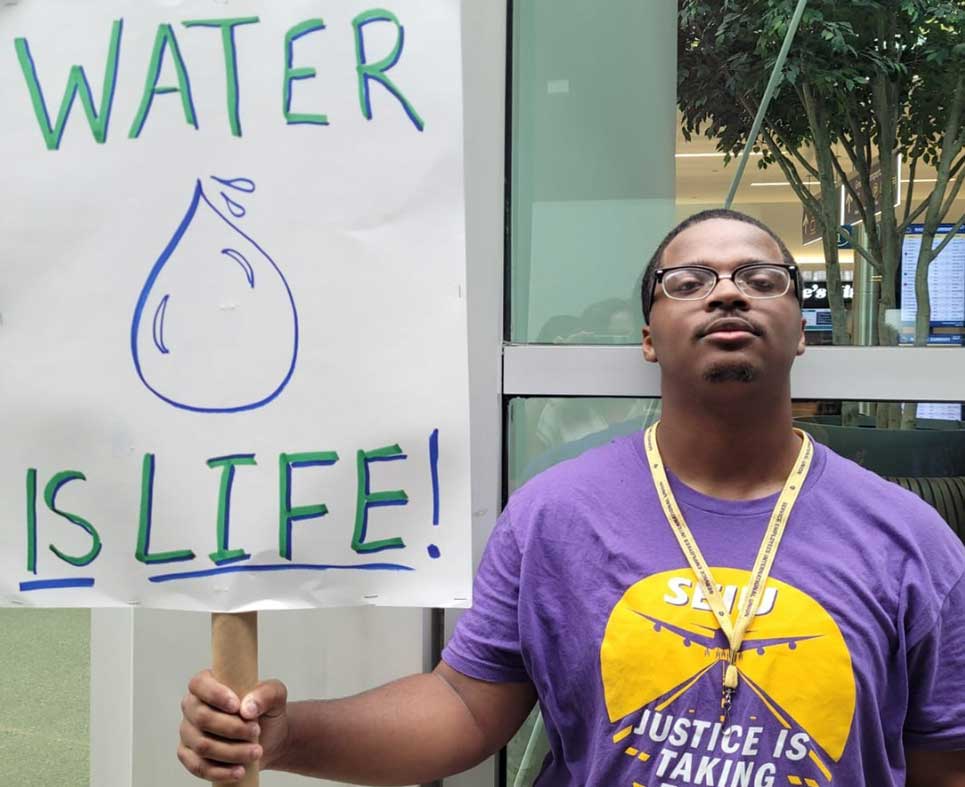 SEIU Airport Worker with a sign that says 'Water is Life'