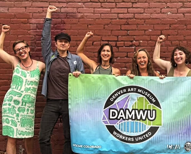 DAMWU members posing for a group photo while holding a banner with their union logo. 