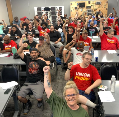 Workers pose for a picture with their fists raised in solidarity.